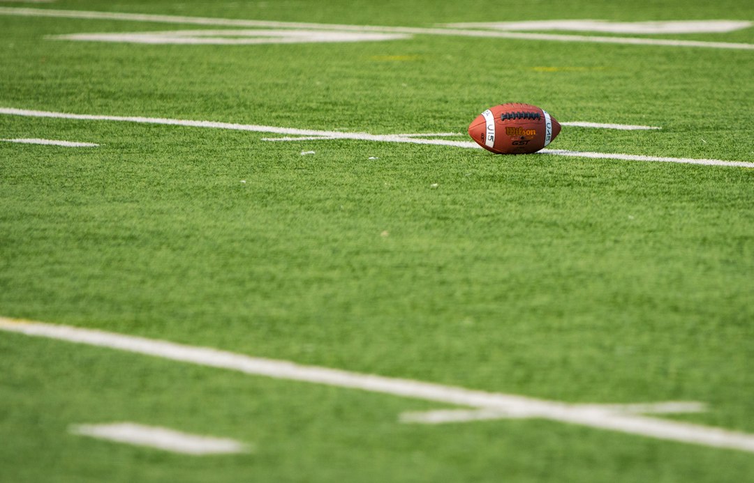 American football resting on a football field