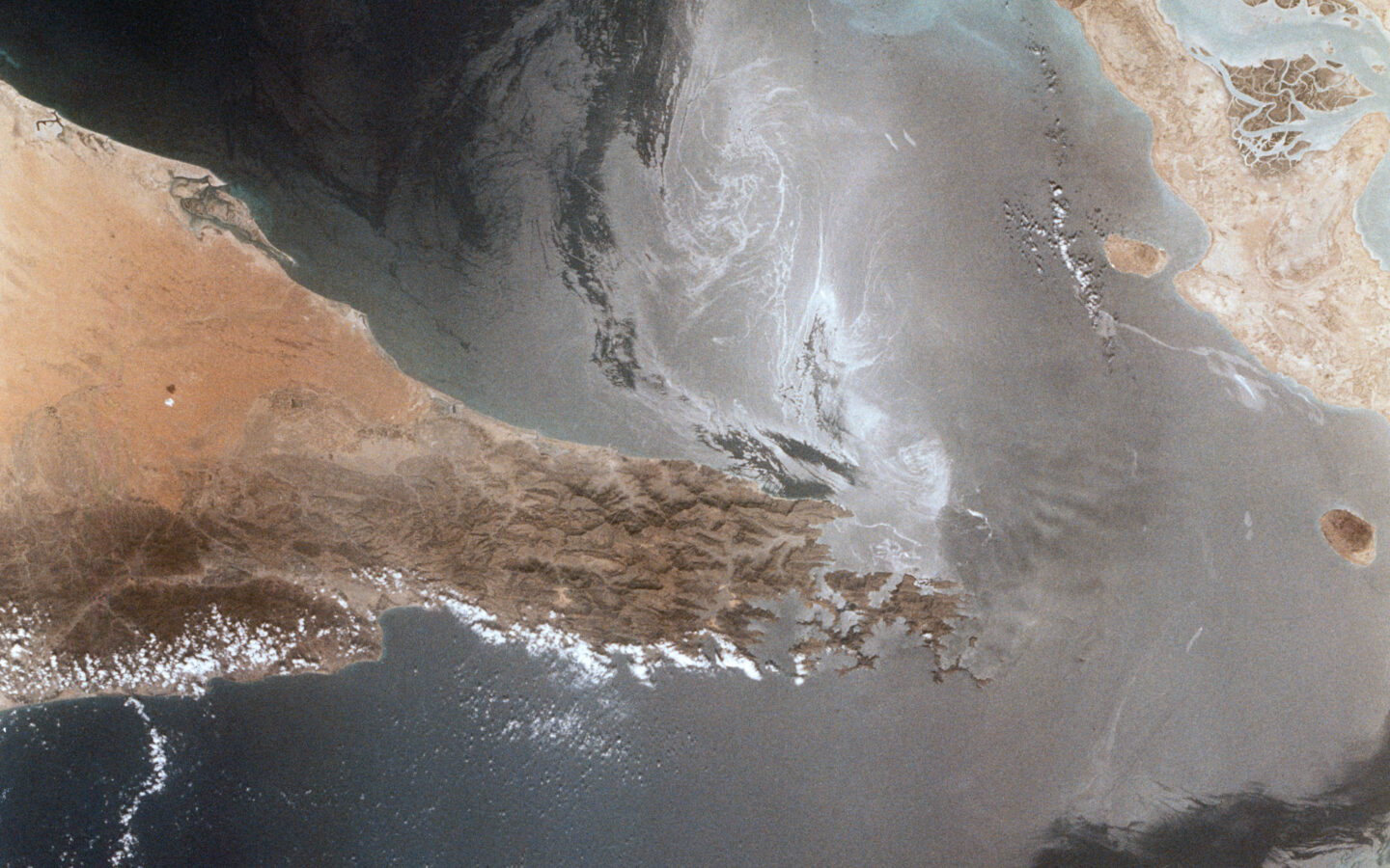 Satellite view of the Strait of Hormuz with ship wakes visible